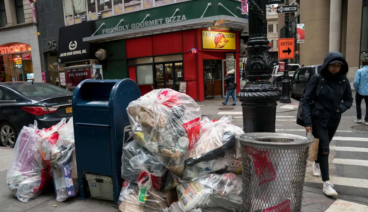 Warga melintas di samping tumpukan sampah di Lower Manhattan, New York City (22/2). Dengan menggunakan data dari Environmental Protection Agency memberi peringkat New York City sebagai kota paling kotor di negara tersebut. (AFP Photo/Drew Angerer)