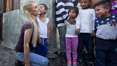Aktris Paris Hilton dicium seorang anak saat mengunjungi keluarga yang terkena dampak gempa bumi pada September 2017 di San Gregorio Atlapulco, Meksiko (12/11). Paris Hilton tampil mengenakan kaos, jeans dan sepatu hitam. (AFP Photo/Antonio Nava)