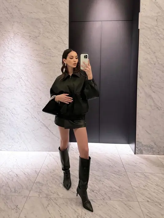 Gaya serba hitam ala Alyssa Daguise. Ia mengenakan atasan berkerah lengan panjang dan mini skirt dari kulit, disempurnakan dengan heels high boots dan mini bag yang semuanya berwarna hitam. [Foto: Instagram/alyssadaguise]