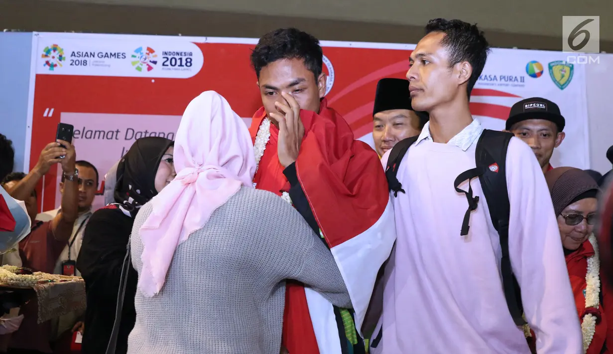 Pelari muda Indonesia, Lalu Muhammad Zohri (tengah) disambut keluarganya saat penyambutan di Terminal 3 Bandara Soetta, Tangerang, Selasa (17/7). Lalu M Zohri meraih emas lari 100m putra U-20 IAAF. (Liputan6.com/Helmi Fithriansyah)