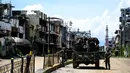 Tentara berpatroli di antara gedung-gedung yang hancur di Kota Marawi, Provinsi Lanao del Sur, Filipina, Kamis (23/5/2019). Setengah wilayah dari kota yang pernah menjadi salah satu tempat terindah di Filipina itu kini hanya beton dan kerangka bangunan akibat serangan udara. (Noel CELIS/AFP)