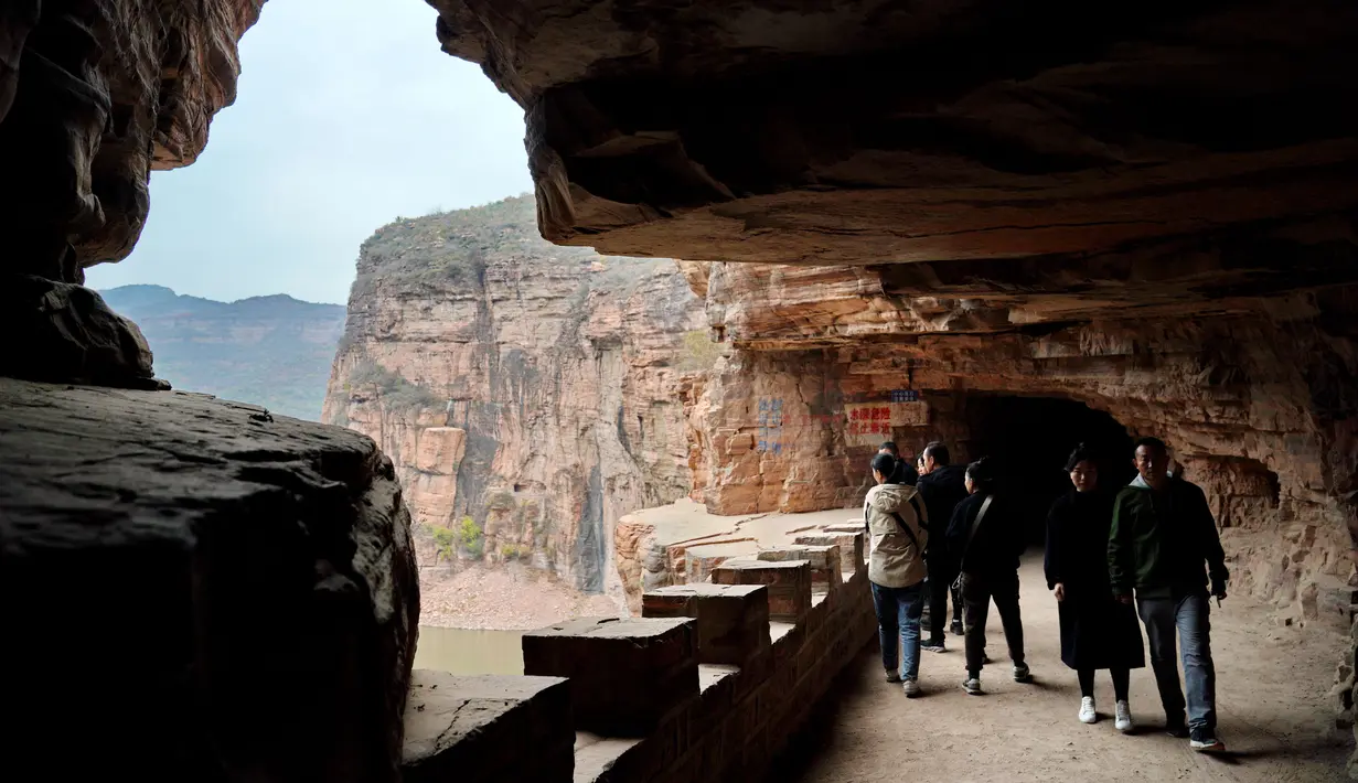 Wisatawan menyusuri jalur di tebing dekat Waduk Xiagou yang berada di Chaiguan, Kota Shahe, Provinsi Hebei, China pada 28 Oktober 2020. Jalur tebing pada dinding Waduk Xiagou ini digali secara manual pada 1970-an. (Xinhua/Mu Yu)