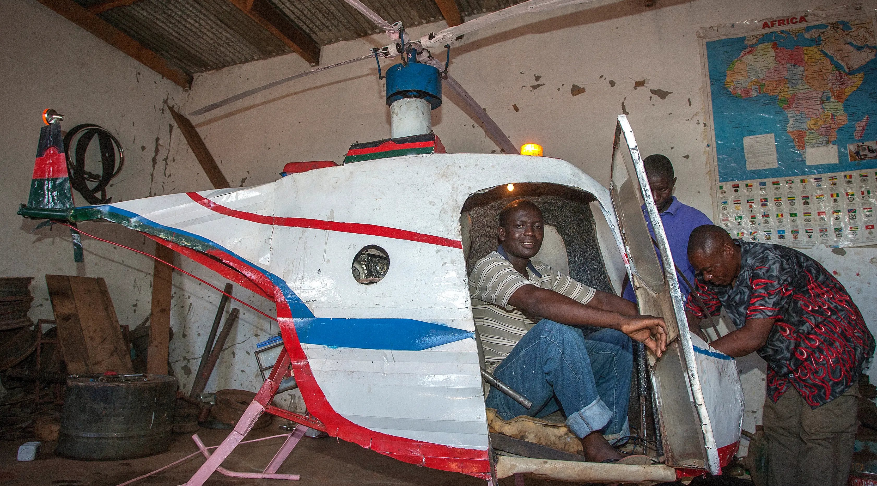 Felix Kambwiri duduk di kokpit helikopter buatannya di garasi rumahnya di Desa Gobede, Malawi, 19 Februari 2016. Helikopter yang dikerjakan sejak empat bulan lalu itu dibuat dari rongsokan besi tua dan fiberglass. (Amos Gumulira/AFP)