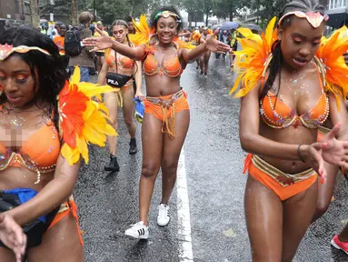 Penari karnaval menari di tengah hujan selama parade hari pertama Karnaval Notting Hill di London barat, Minggu (26/8). Karnaval Notting Hill yang merupakan pawai jalanan terbesar di Eropa diadakan setiap tahun sejak tahun 1966. (AFP/Daniel LEAL-OLIVAS)