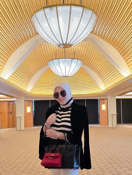 <p>Syahrini mengunggah foto saat berada di Singapura. Dia mengenakan outfit berwarna hitam putih dan menutupi bagian perutnya dengan dua buah tas. (foto: Instagram/ princessyahrini)</p>