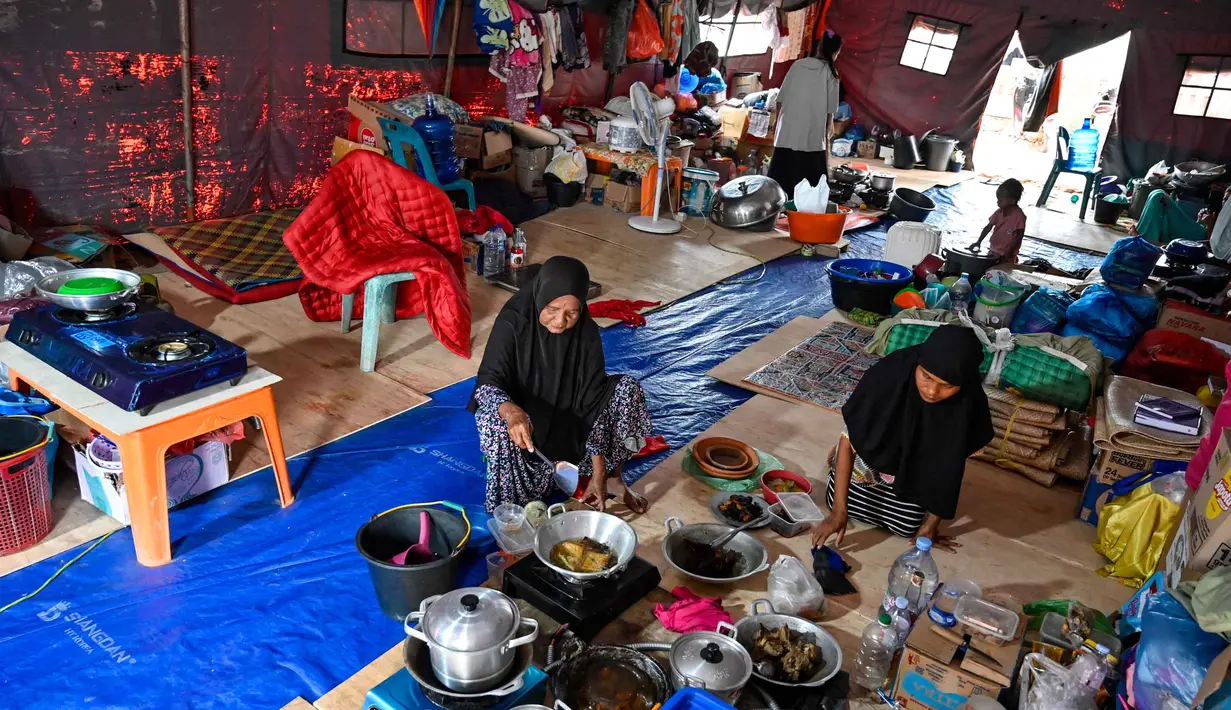 Untuk diketahui, sudah hampir tiga bulan berlalu sejak bencana melanda, namun pembangunan hunian sementara (Huntara) yang dijanjikan bagi para penyintas belum juga rampung. Tampak dalam foto, para pengungsi memasak makanan untuk berbuka puasa Ramadan di tenda yang menampung para korban banjir di Meurah Dua, Kabupaten Pidie Jaya, Provinsi Aceh, pada 21 Februari 2026, setelah banjir dan tanah longsor dahsyat melanda Sumatra, akhir November 2025 lalu. (CHAIDEER MAHYUDDIN/AFP)