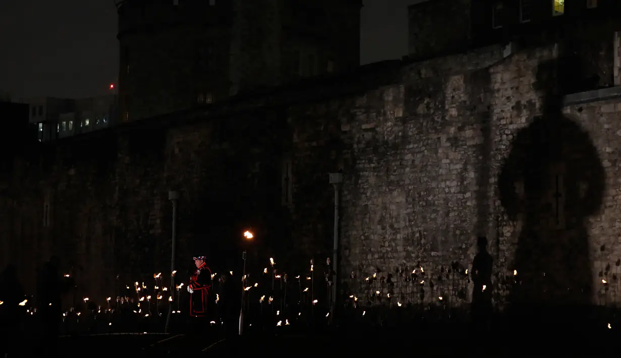 Yeoman Warders atau 'Beefeaters' berdiri di antara ribuan lilin di parit kering Tower of London, Inggris, Selasa (6/11). Lilin itu untuk menandai 100 tahun akhir Perang Dunia I. (AP Photo/Alastair Grant)