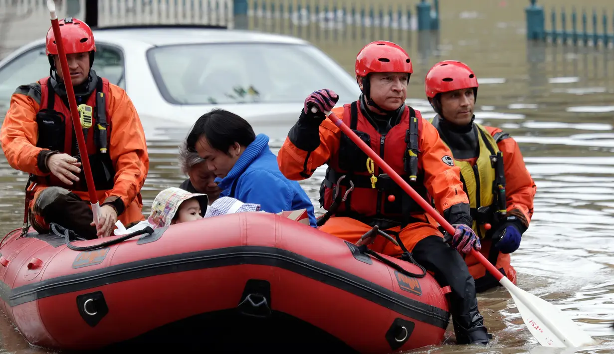 Warga dievakuasi tim SAR menggunakan perahu karet menerobos banjir di San Jose, California, Selasa (21/2). Banjir terjadi akibat meluapnya Sungai Coyote Creek yang tidak mampu menampung debit air setelah hujan lebat. (AP Photo/Marcio Jose Sanchez)