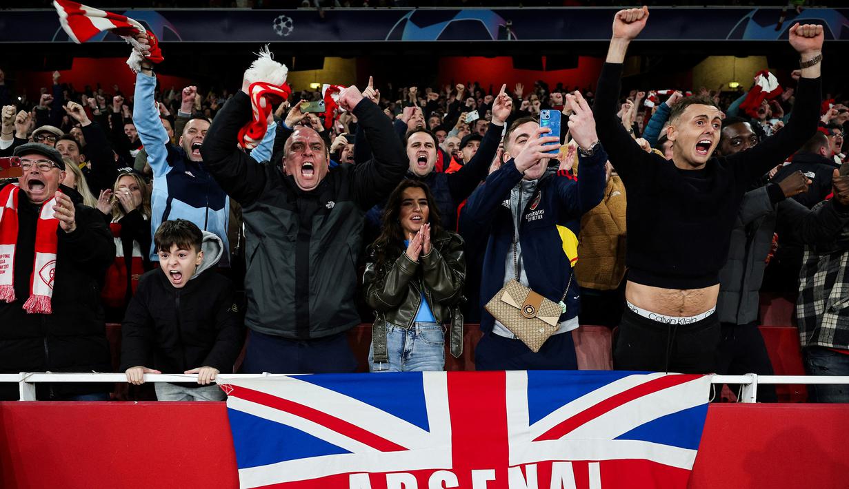 Pendukung Arsenal merayakan kemenangan timnya atas Porto pada laga leg kedua 16 besar Liga Champions 2023/2024 di Emirates Stadium, London, Inggris, Rabu (13/03/2024). (AFP/Adrian Dennis)