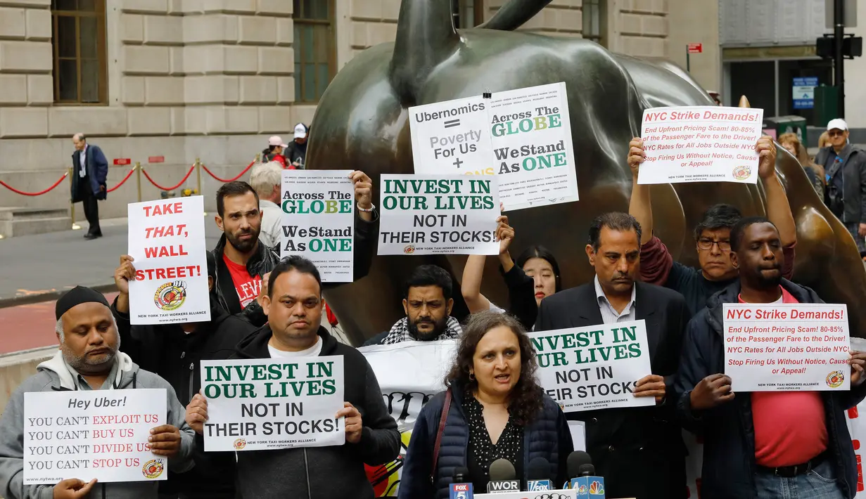 Sopir taksi online Uber menggelar protes di sebelah patung Charging Bull di distrik keuangan New York, AS, Rabu (8/5/2019). Para sopir menuntut kenaikan tarif per kilometer dan dikuranginya komisi yang harus dibayar kepada Uber. (AP Photo/Mark Lennihan)