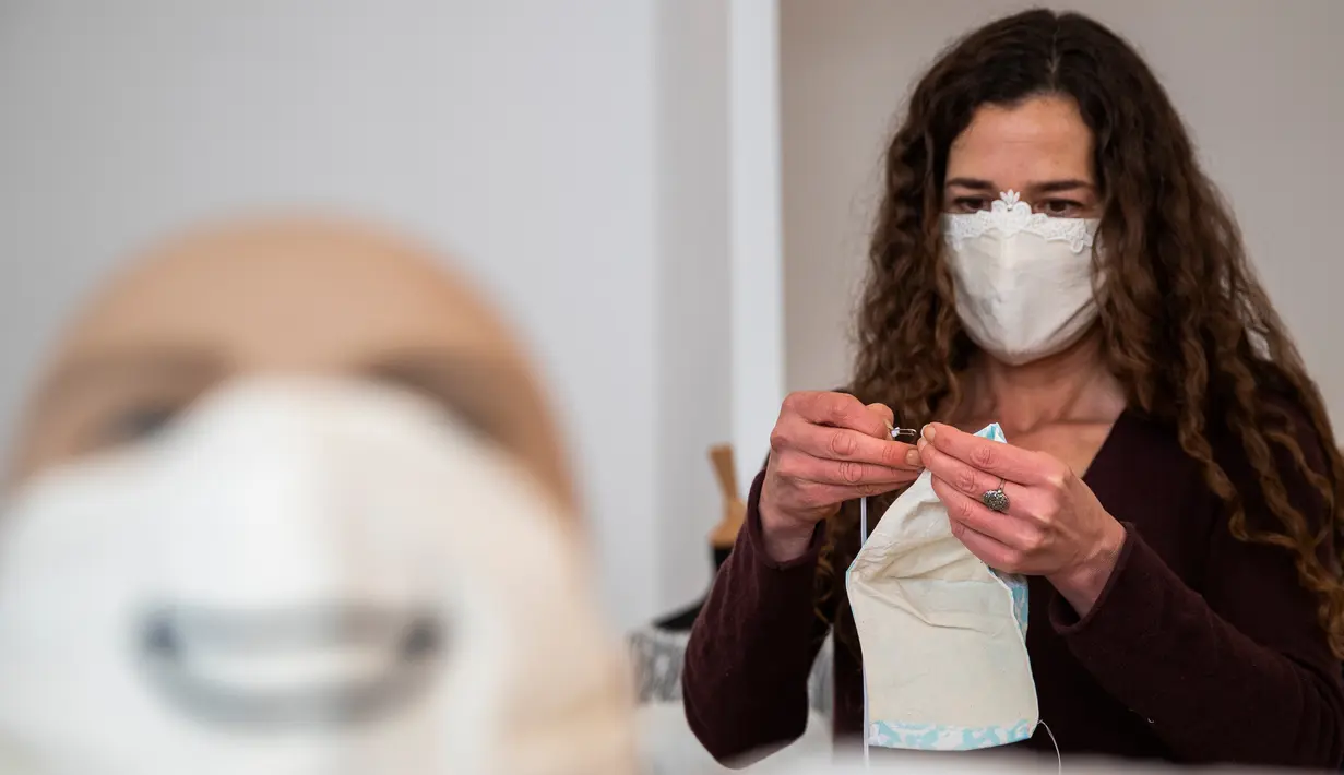 Desainer Friederike Jorzig membuat masker masker untuk gaun pernikahan di tokonya di Berlin, Jerman (31/3/2020).  Frederike Jorzig membuat gaun pernikahan yang dirancang lengkap dengan masker untuk menghindari penularan Covid-19  di tokonya di distrik Schoeneberg Berlin. (AFP/Odd Andersen)