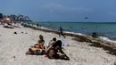 Orang-orang menghabiskan waktu di Miami Beach, Florida, Rabu (10/6/2020). Pantai Miami dibuka hari ini untuk pertama kalinya setelah hampir tiga bulan ditutup guna menekan jumlah penyebaran corona Covid-19. (CHANDAN KHANNA / AFP)