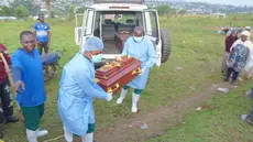 Petugas yang mengenakan pakaian pelindung menurunkan peti mati berisi jenazah balita berusia 3 tahun yang meninggal akibat Ebola saat pemakaman di Bunia, Provinsi Ituri, Kongo timur, Selasa, 18 Agustus 2026. (Foto AP/Dieudonne Dirole)