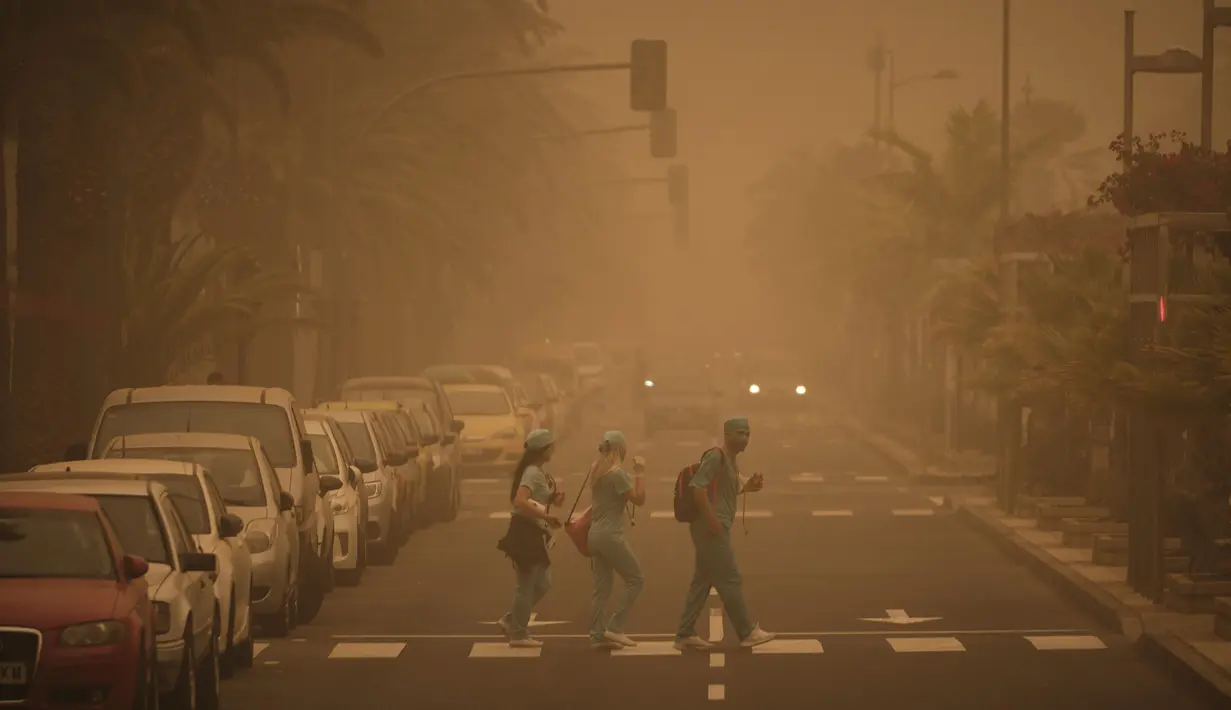 Sejumlah orang menyeberangi jalan saat badai pasir Gurun Sahara menerjang Santa Cruz de Tenerife, Kepulauan Canary, Spanyol, Minggu (23/2/2020). Pemerintah setempat menyarankan penduduk untuk tetap di dalam rumah. (AP Photo/Andres Gutierrez)