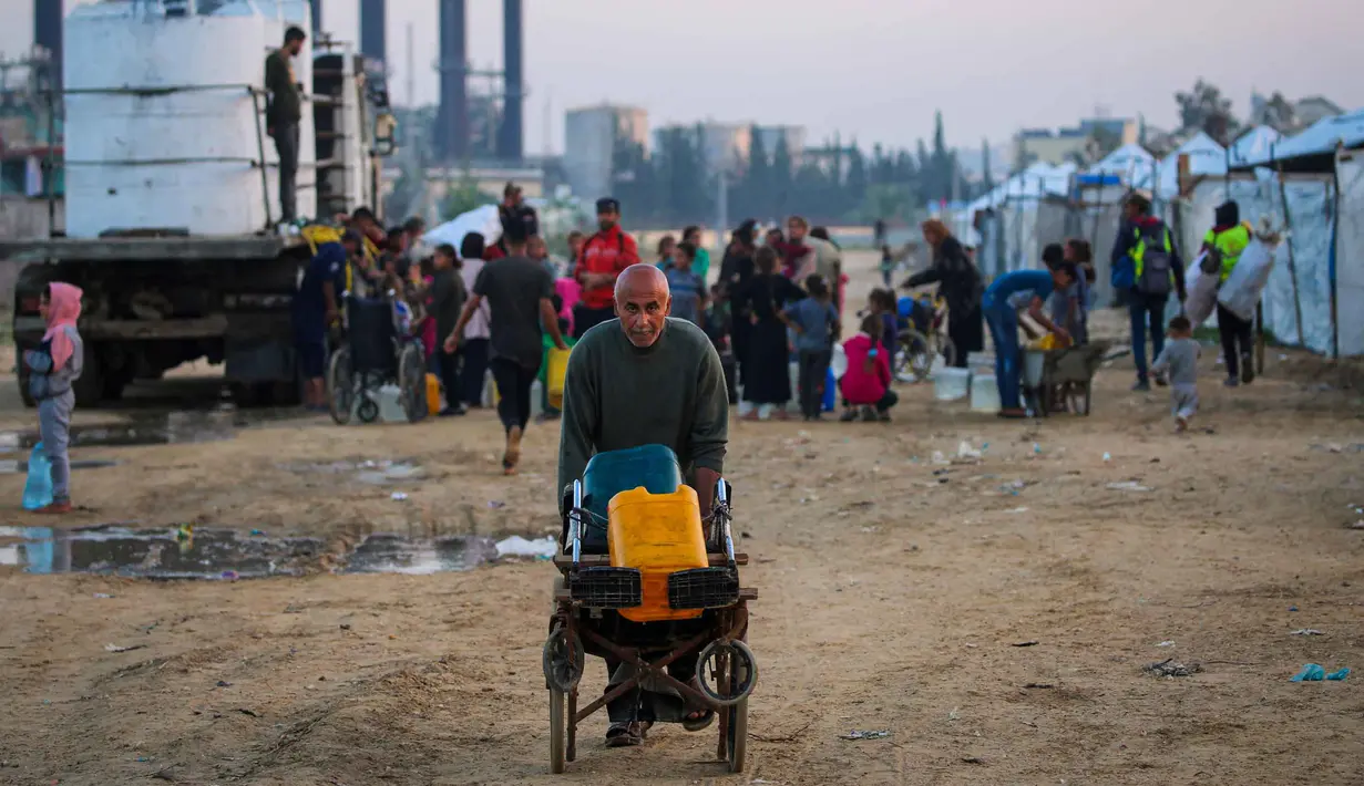 Laporan Perserikatan Bangsa Bangsa (PBB) per Oktober 2025 menyebutkan bahwa sekitar 84% infrastruktur di Gaza, termasuk jaringan air bersih, telah hancur. Pipa-pipa utama rusak parah, menyebabkan jaringan distribusi air lumpuh. Tampak dalam foto, orang-orang mengisi wadah air mereka di kamp Nuseirat untuk pengungsi Palestina di Jalur Gaza tengah pada Kamis 4 Desember 2025. (Eyad Baba/AFP)
