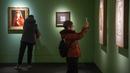 Seorang perempuan yang mengenakan masker mengambil foto sebuah lukisan di sebuah galeri di Museum Seni Nasional China di Beijing, Rabu (1/2/2023). Pengunjung terus berduyun-duyun ke museum, situs bersejarah, dan tempat wisata di ibu kota China saat periode liburan Tahun Baru Imlek berakhir. (AP Photo/Mark Schiefelbein)