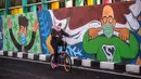 Pesepeda melintas di dekat dinding bermural yang mengajak orang untuk memakai masker di tengah pandemi Covid-19 di Surabaya, Jawa Timur, Minggu (25/10/2020). Dinding itu dipenuhi dengan pesan untuk mematuhi protokol kesehatan di tengah pandemi Covid-19. (Juni Kriswanto/AFP)