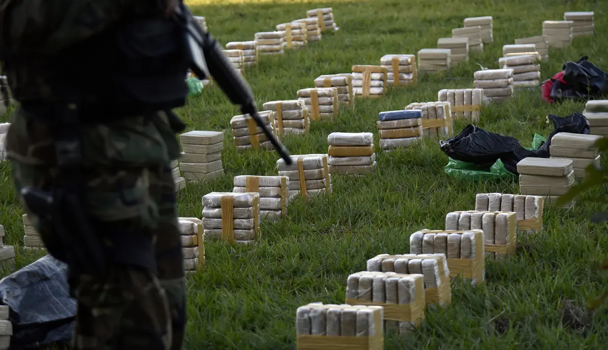 Petugas berjaga di dekat tumpukan satu ton kokain dalam paket yang disita di lokasi Baures saat jumpa pers di Trinidad, El Beni, Bolivia (19/7). Kabarnya obat terlarang tersebut akan dikirim ke Brasil. (AFP Photo/Ar/Aizar Raldes)