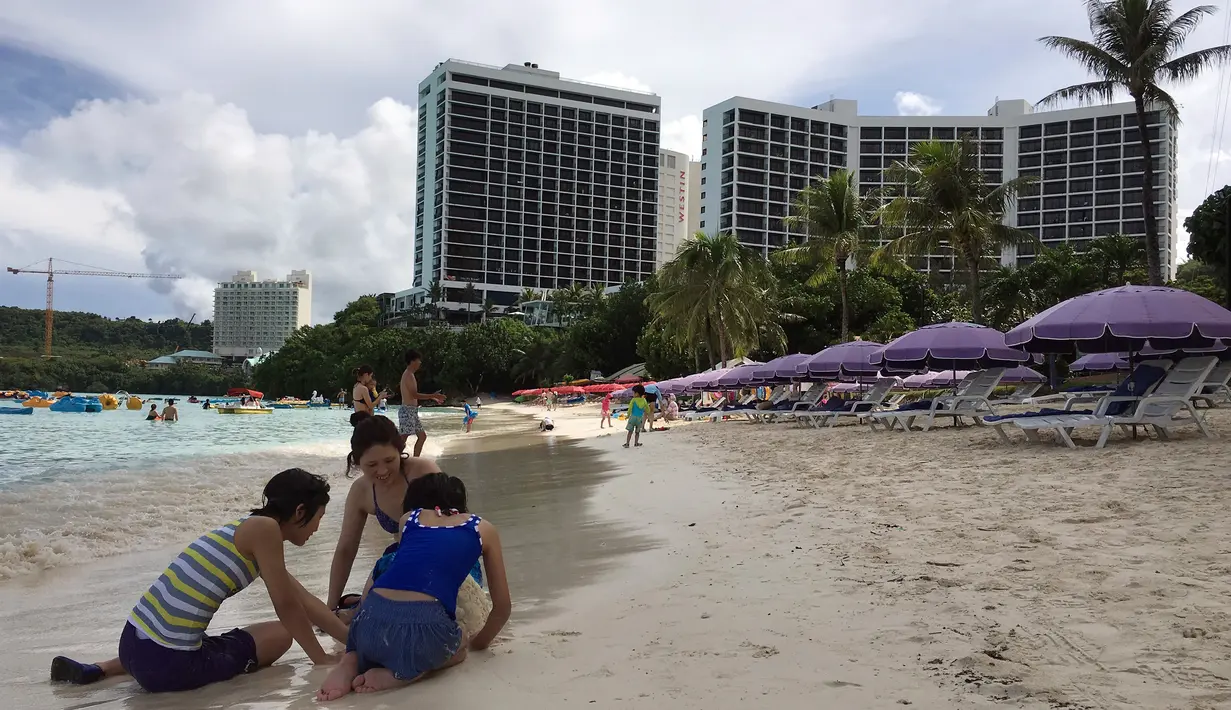 Sebuah keluarga bermain pasir di pantai Tumon, Guam, Kamis (10/8). Meskipun suasana ketegangan di kawasan itu meningkat terkait ancaman bom nuklir Korea Utara, warga Guam tetap beraktivitas seperti biasa. (AP Photo/Tassanee Vejpongsa)