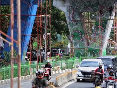 Pengendara melintas dekat dinding Jalan Layang Pesing yang berhias mural di Jakarta Barat, Sabtu (7/12/2019). Mural pada jalan layang sepanjang 1,5 kilometer tersebut merupakan bagian dari program Pemerintah Provinsi DKI Jakarta dalam mempercantik Ibu Kota. (Liputan6.com/Johan Tallo)