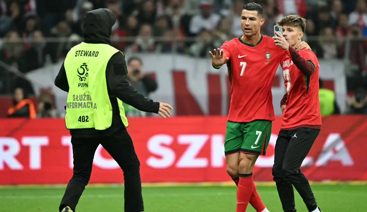 Seorang steward berlari untuk mengusir salah satu suporter yang masuk ke lapangan untuk berswafoto dengan pemain bintang, Cristiano Ronaldo selama pertandingan sepak bola UEFA Nations League 2024/2025, Liga A Grup A1 Polandia vs Portugal di Stadion PGE Narodowy, Warsawa, Polandia pada Sabtu 12 Oktober 2024 atau Minggu (13/10/2024) dini hari WIB. (Sergei GAPON/AFP)