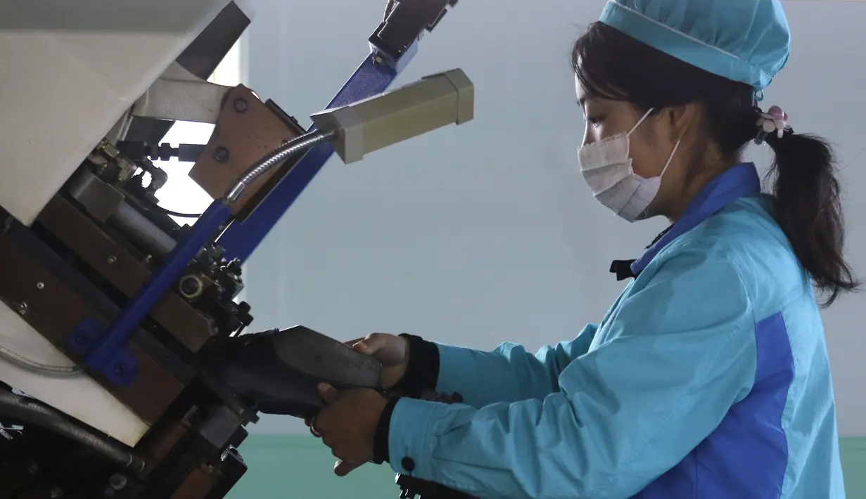 Pekerja memakai masker di Pabrik Sepatu Kulit Wonsan, tempat mereka memproduksi sepatu kulit buatan tangan di Wonsan, Provinsi Kangwon, Korea Utara pada 28 Oktober 2020. (AP Photo/Jon Chol Jin)