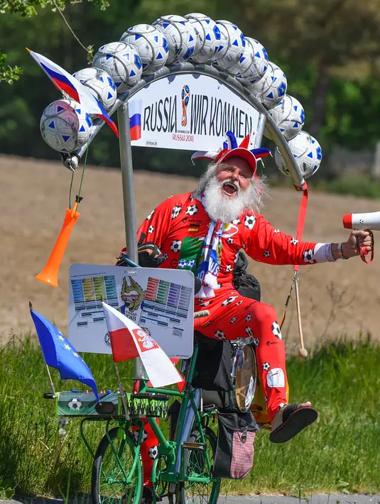 Tingkah lucu perancang sepeda asal Jerman, Dieter Senft atau Didi the Devil saat mengendarai sepeda unik buatannya di Briesen, Jerman Timur, Senin (7/5). Aksi itu dia lakukan untuk mempromosikan Piala Dunia 2018. (Patrick Pleu/dpa/AFP)