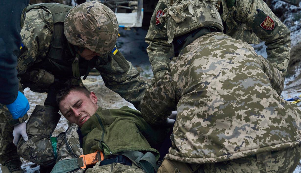 Petugas medis militer memberikan pertolongan pertama kepada tentara yang terluka dekat Kremenna di wilayah Luhansk, Ukraina, 16 Januari 2023. Hingga saat ini pejabat Ukraina menolak untuk mengonfirmasi jumlah korban dalam perangnya dengan Rusia, setelah ketua Komisi Uni Eropa pada akhir November 2022 lalu memperkirakan bahwa "lebih dari 20.000 warga sipil dan 100.000 tentara Ukraina telah tewas di Ukraina hingga saat ini." (AP Photo/LIBKOS)