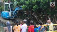 Warga mengamati alat berat yang dioperasikan untuk pengerukan di Kali Mampang, Pondok Jaya, Sabtu (19/2/2022). Pengadilan Tata Usaha Negara (PTUN) Jakarta mengabulkan gugatan warga pada 19-21 Februari 2021 terkait program pencegahan banjir yang dilakukan Pemprov DKI. (Liputan6.com/Herman Zakharia)