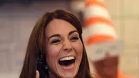 Duchess of Cambridge, Kate Middleton tertawa lepas sambil menggenggam gagang telepon saat menjadi broker dalam acara amal tahunan ICAP di London, Inggris, Rabu (9/12/2015). (AFP PHOTO/POOL/JEREMY Selwyn)