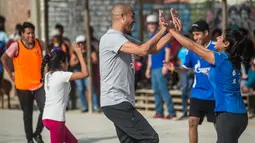 Mantan pemain bola Juventus, David Trezeguet merayakan golnysa saat bermain bola bersama anak-anak di komunitas San Pablo Mirador, Peru (13/7). (AFP Photo/Ernesto Benavides)