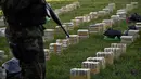 Petugas berjaga di dekat tumpukan satu ton kokain dalam paket yang disita di lokasi Baures saat jumpa pers di Trinidad, El Beni, Bolivia (19/7). Kabarnya obat terlarang tersebut akan dikirim ke Brasil. (AFP Photo/Ar/Aizar Raldes)