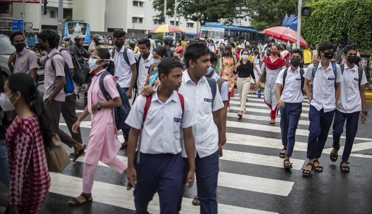 Pejalan kaki yang mengenakan masker berjalan melalui zebra cross di Kochi, negara bagian Kerala, India, Rabu (6/7/2022). Negara bagian selatan itu telah mewajibkan penggunaan masker di tempat-tempat umum menyusul meningkatnya kasus COVID-19. (AP Photo/ RS Iyer)