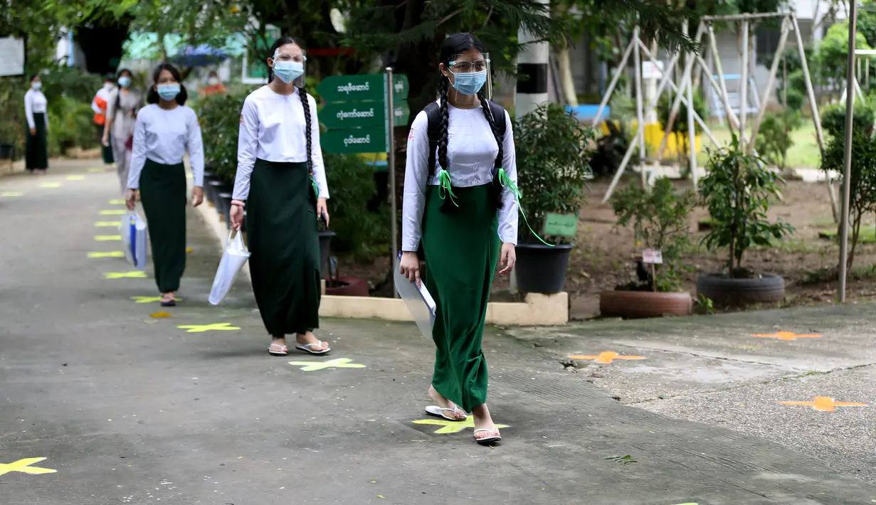 Para siswa yang mengenakan pelindung wajah dan masker berjalan dengan menjaga jarak sosial pada hari pendaftaran sekolah di Yangon, Myanmar (13/7/2020). Myanmar sejak Selasa (7/7) memulai pendaftaran sekolah untuk tahun ajaran 2020-2021, yang tertunda akibat pandemi COVID-19. (Xinhua/U Aung)