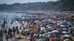 Para pengunjung berjemur menikmati sinar matahari di Pantai Bournemouth, Selatan Inggris pada Selasa 26 Mei 2026, saat kondisi gelombang panas menyebar ke sebagian wilayah tenggara Inggris dan London. (JUSTIN TALLIS/AFP)