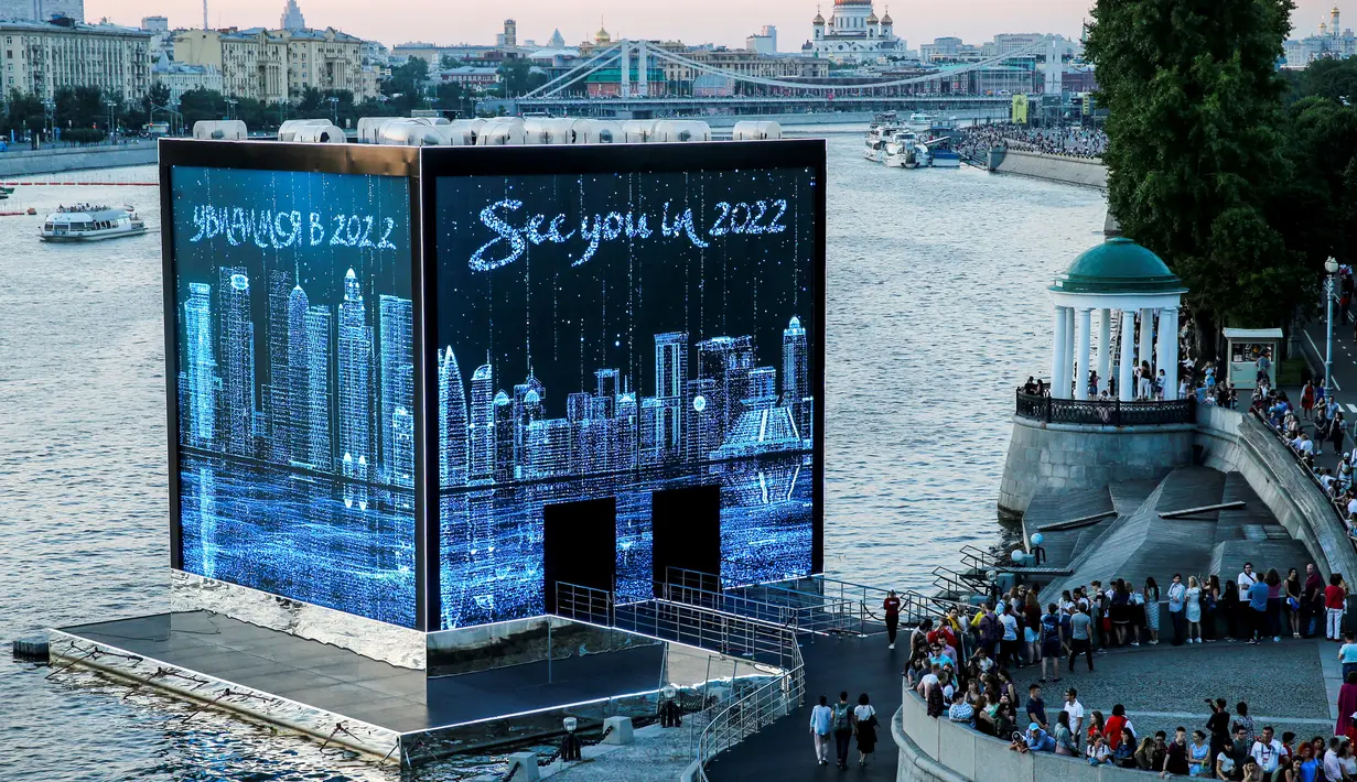 Warga melihat ke Majlis Qatar yang menyajikan pertunjukan cahaya di Gorky Park, Moskow, Rusia, Kamis (12/7). Qatar akan menjadi tuan rumah Piala Dunia 2022. (Maxim ZMEYEV/AFP)