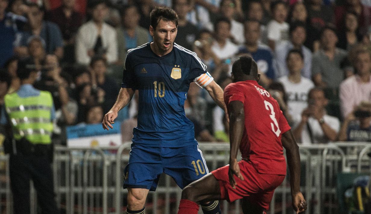 Striker Argentina, Lionel Messi berusaha melewati penjagaan pemain Timnas Hong Kong, Agbo Wisdom Fofo pada laga persahabatan internasional di Hong Kong Stadium, Hong Kong (14/10/2014). (AFP/Anthony Wallace)