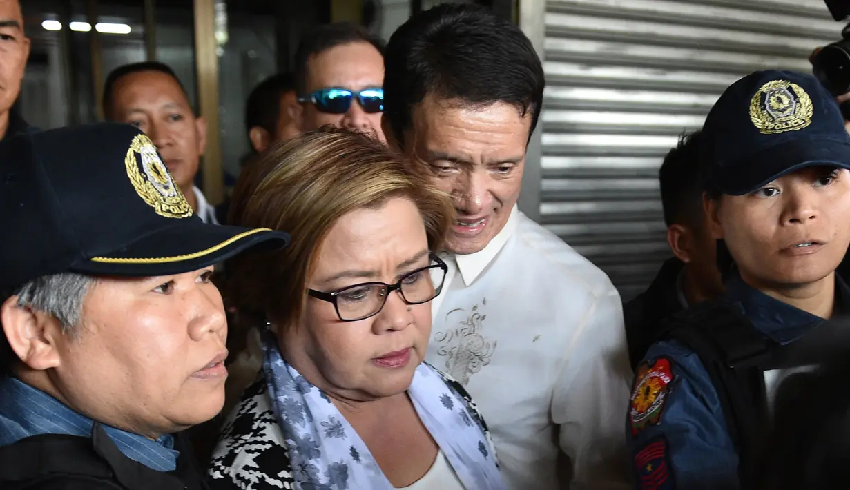 Senator Filipina, Leila de Lima, dikawal aparat keamanan dan didampingi pengacara saat penangkapannya di kota Pasay, selatan Manila, Jumat (24/2). Leila de Lima dituding menerima uang dari para pengedar narkoba di penjara-penjara Filipina (TED ALJIBE/AFP)