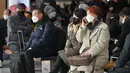 Orang-orang yang memakai masker duduk di bangku di stasiun kereta Seoul, setelah Korea Selatan mencabut mandat masker dalam ruangan, Senin (30/1/2023). Kewajiban itu diberlakukan selama lebih dari 2 tahun dan diakhiri karena kasus COVID-19 yang terus menurun. (Jung Yeon-je / AFP)