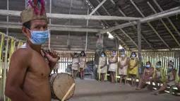 Suku Tikuna berpose mengenakan masker di tengah kekhawatiran virus corona Covid-19 di Leticia, Departemen Amazonas, Kolombia pada 8 Juni 2020. Kasus virus corona ini meningkatkan kekhawatiran akan resiko penyebaran ke masyarakat adat yang rentan dan berada di pedalaman. (Tatiana de NEVO/AFP)