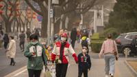 Orang-orang yang memakai masker berjalan di sepanjang jalan pada siang hari dengan kualitas udara yang buruk di Beijing, Jumat, 10 Maret 2023. Ibu kota ini dulu juga terkenal dengan debu musim semi dan badai pasir yang disebabkan oleh angin yang bertiup dari perbukitan loess di sepanjang bagian atas Sungai Kuning ke arah barat. (AP Photo/Mark Schiefelbein)