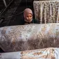 Seorang wanita mewarnai kain batik saat proses pembuatan di Sidoarjo, Jawa Timur, Sabtu (1/10/2022). Indonesia akan memperingati Hari Batik Nasional pada 2 Oktober. (JUNI KRISWANTO/AFP)