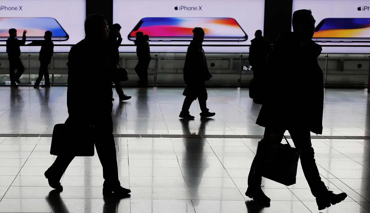Sejumlah warga melintas di depan papan iklan di Seoul Station di Seoul, Korea Selatan (19/2). (AFP Photo/David Gannon)