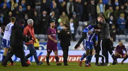 Seorang suporter mendekati Striker Manchester City Sergio Aguero dari belakang dan terlihat berusaha mengatakan sesuatu seusai babak kelima Piala FA di markas Wigan Athletic, Stadion DW, Senin (19/2). Hal itu memancing kemarahan Aguero. (Oli SCARFF/AFP)