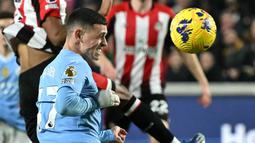 Pemain Manchester City, Phil Foden, mencetak gol melalui tandukan kepala ke gawang Brentford pada laga Liga Inggris di Stadion Gtech Community, Selasa (6/2/2024). Foden memborong tiga gol. (AFP/Ben Stansall)