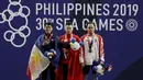 Lifter Suratman (kanan) saat naik podium usai mendapatkan medali perunggu SEA Games 2019 cabang angkat besi nomor 55 kg di Stadion Rizal Memorial, Manila, Minggu (1/12). Dirinya meraih perak dengan total angkatan 250 kg. (Bola.com/M Iqbal Ichsan)