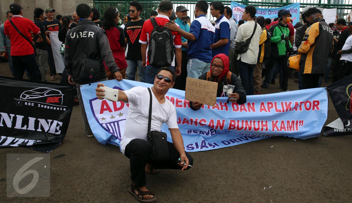 Dua orang pria berselfie saat menggelar unjuk rasa di depan Gedung MPR/DPR, Jakarta, Senin (27/2). Unjuk rasa tersebut memprotes kebijakan-kebijakan yang merugikan mereka. (Liputan6.com/Johan Tallo)