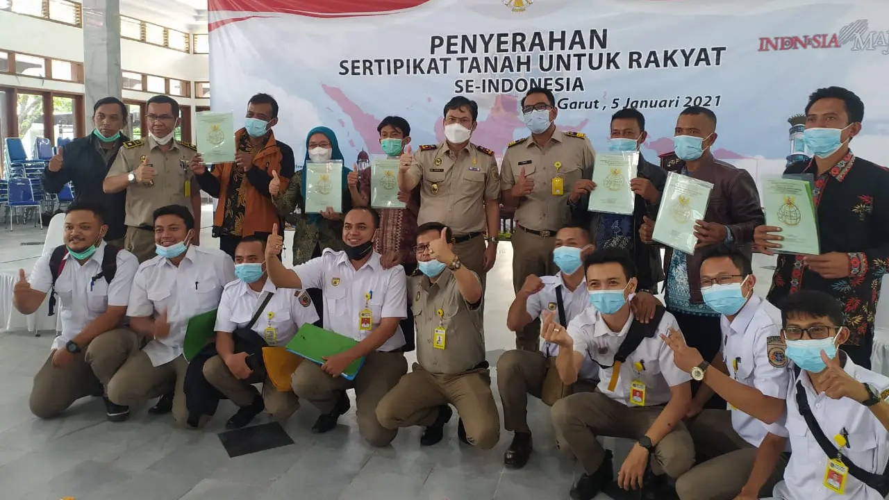 Para pegawai BPN Garut tengah berfoto bersama masyarakat penerima pemberian sertifikat tanah gratis dari pemerintah.