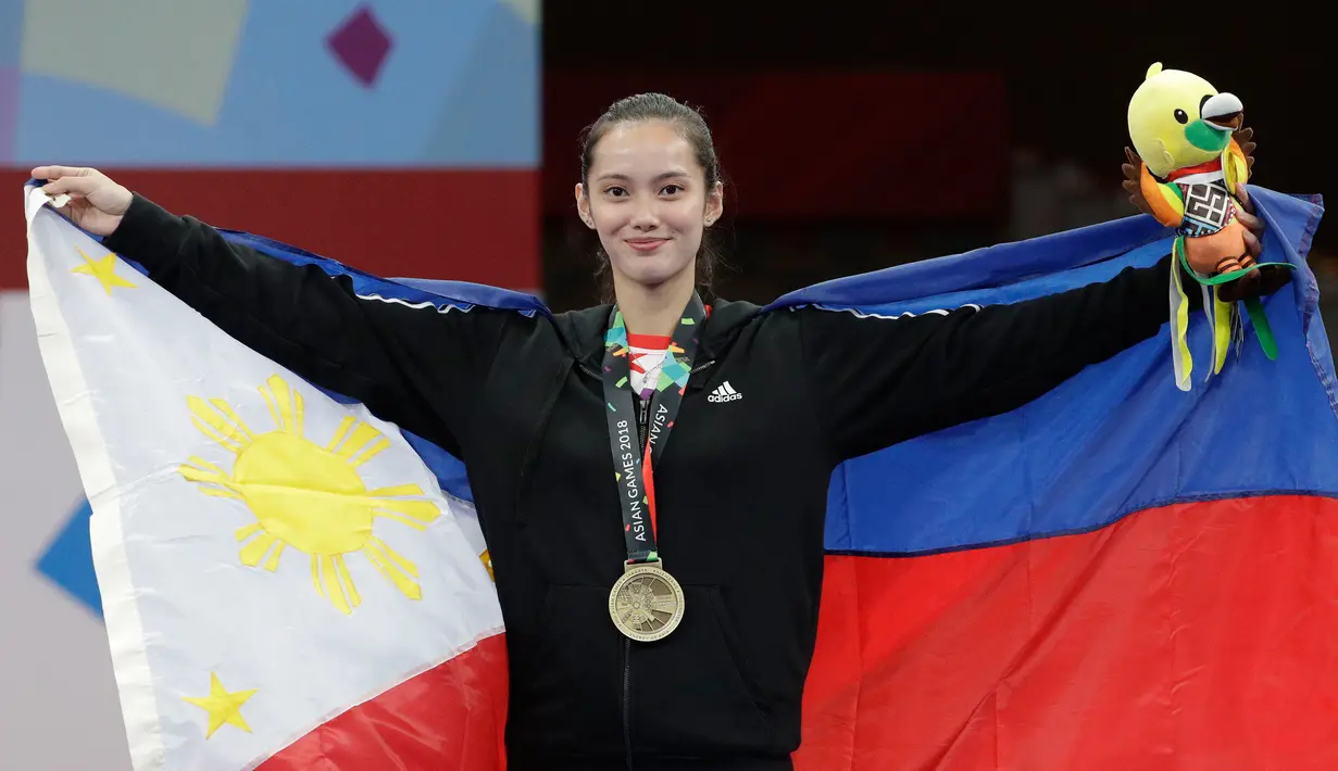 Atlet wushu Filipina peraih medali perunggu, Agatha Wong mengibarkan bendera nasionalnya usai pertandingan wushu taijijian putri Asian Games 2018 di Jakarta, Senin (20/8). (AP Photo/Aaron Favila)