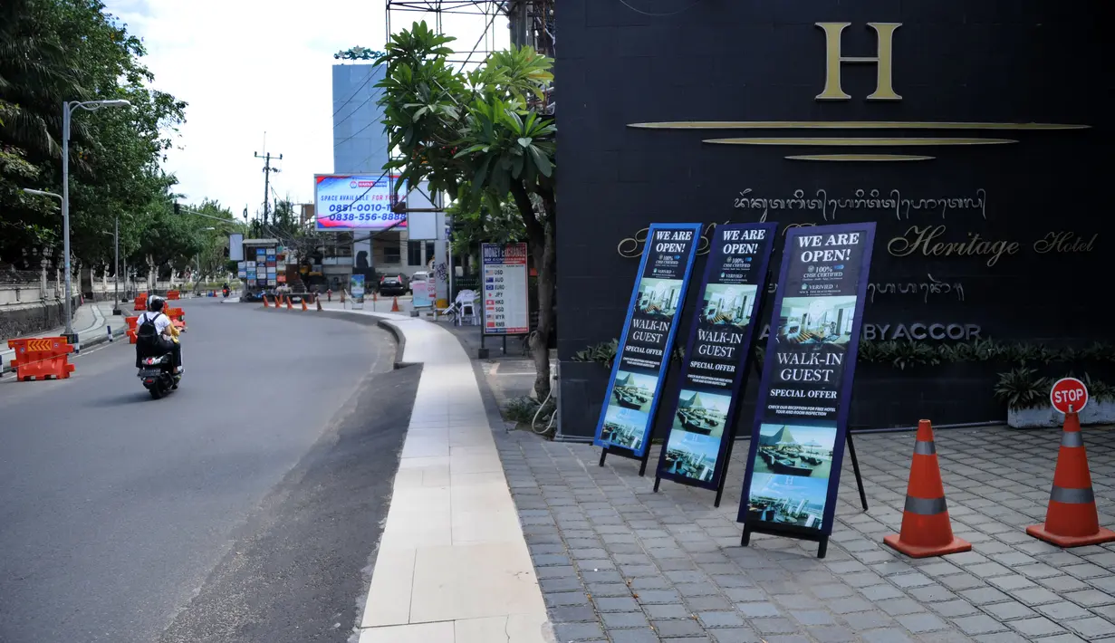 Papan nama promosi terlihat di luar hotel di jalan utama yang sepi saat Pemberlakuan Pembatasan Kegiatan Masyarakat (PPKM) Level 3 di Kuta, Badung, Bali, Jumat (23/7/2021). Selama PPKM Level 3 di Bali, tempat usaha boleh buka hingga pukul 21.00 Wita. (SONNY TUMBELAKA/AFP)
